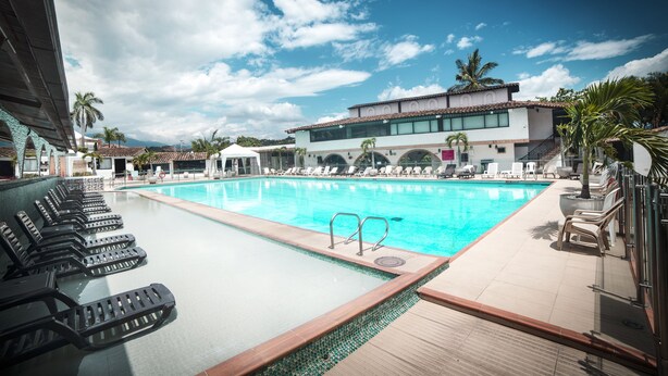Ein Poolbereich mit Liegestühlen und einem Gebäude im Hintergrund.