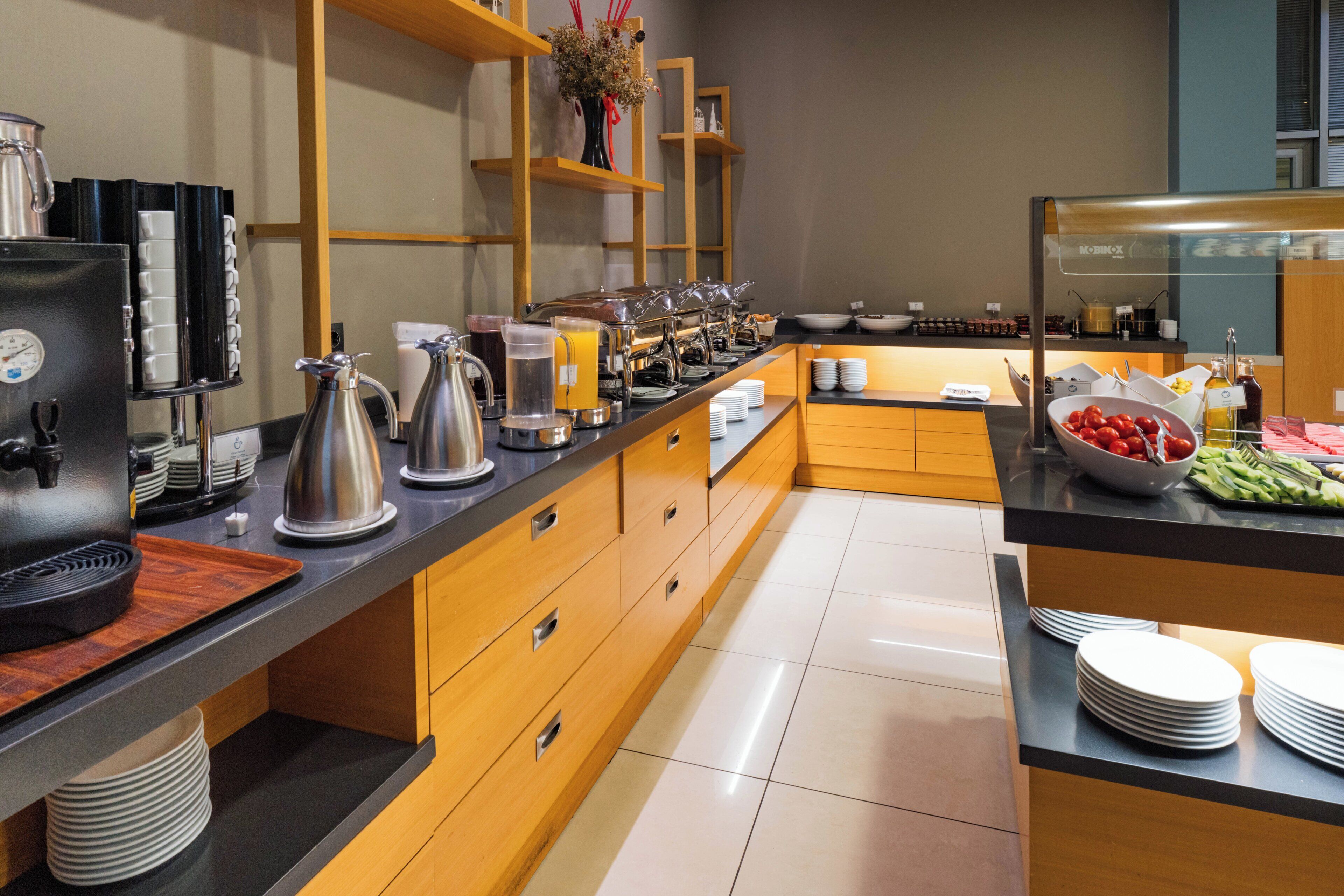 A modern breakfast buffet with stainless steel appliances, wooden cabinets, and a variety of food options.