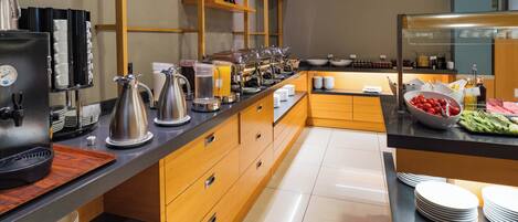 A modern breakfast buffet with stainless steel appliances, wooden cabinets, and a variety of food options.