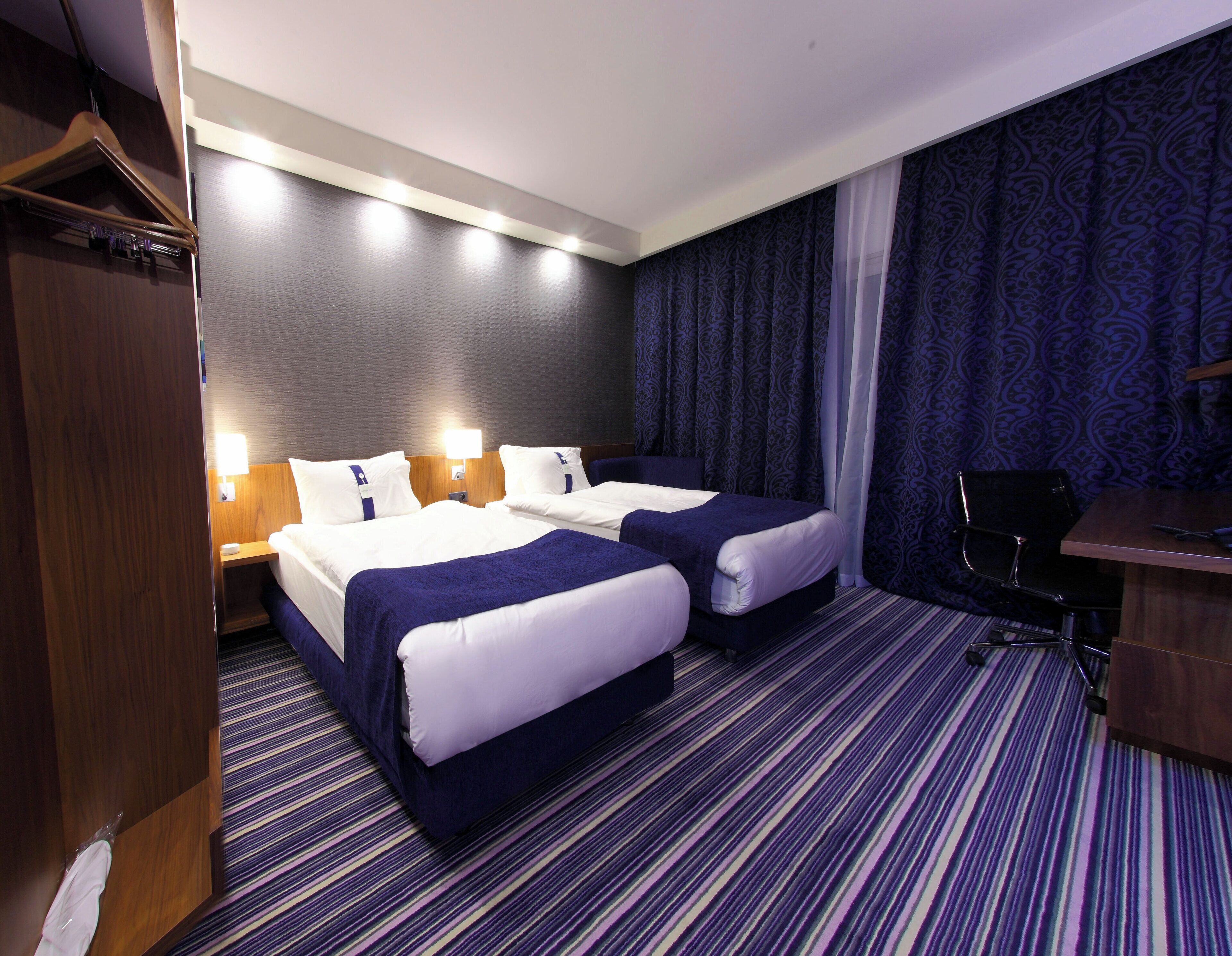 Una habitación de hotel con dos camas, un escritorio y un armario.