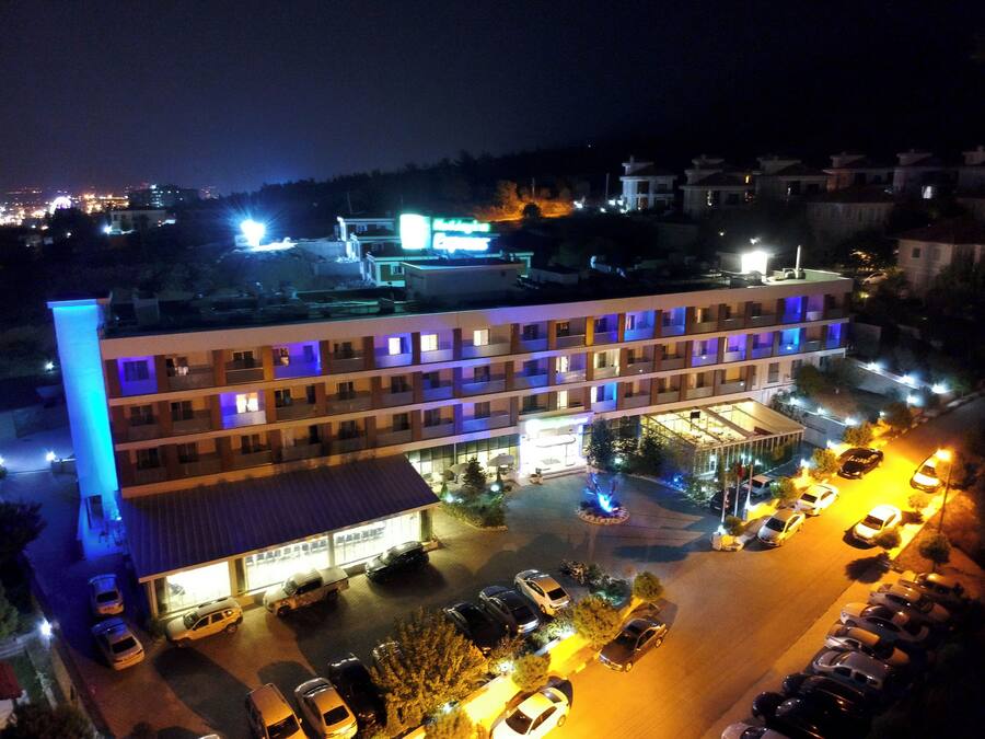 Un hotel de varios pisos con estacionamiento y un pequeño espacio al aire libre con una fuente.