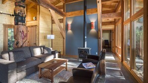 A cozy log cabin interior with a sofa, coffee table, and a fireplace. - Wya Point Resort (Ucluelet)