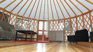 A yurt interior with a wooden lattice structure, a sofa, a cabinet, and a small table. - Wya Point Resort (Ucluelet)