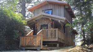 A wooden cabin with a balcony, surrounded by trees. - Wya Point Resort (Ucluelet)