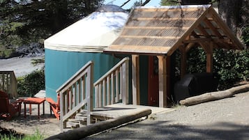 A rustic cabin with a covered porch, a small wooden structure, and outdoor seating.