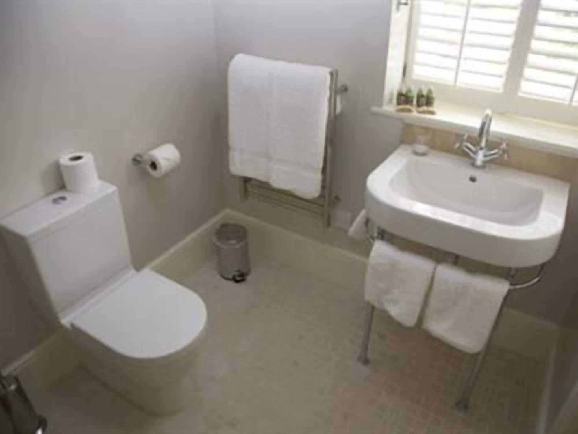 A small, clean bathroom with a toilet, sink, and window.