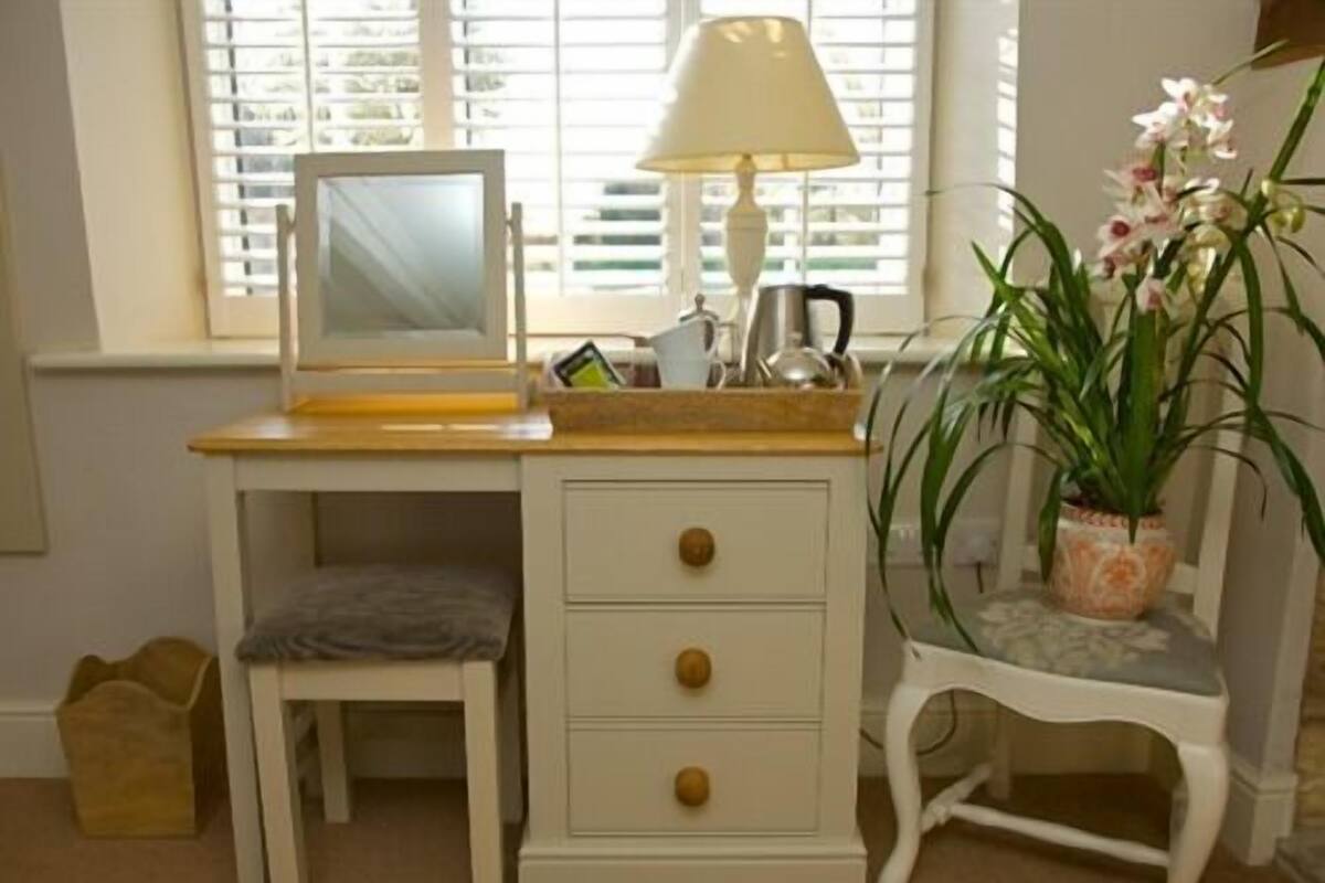 A white desk with a computer, a lamp, and a potted plant.