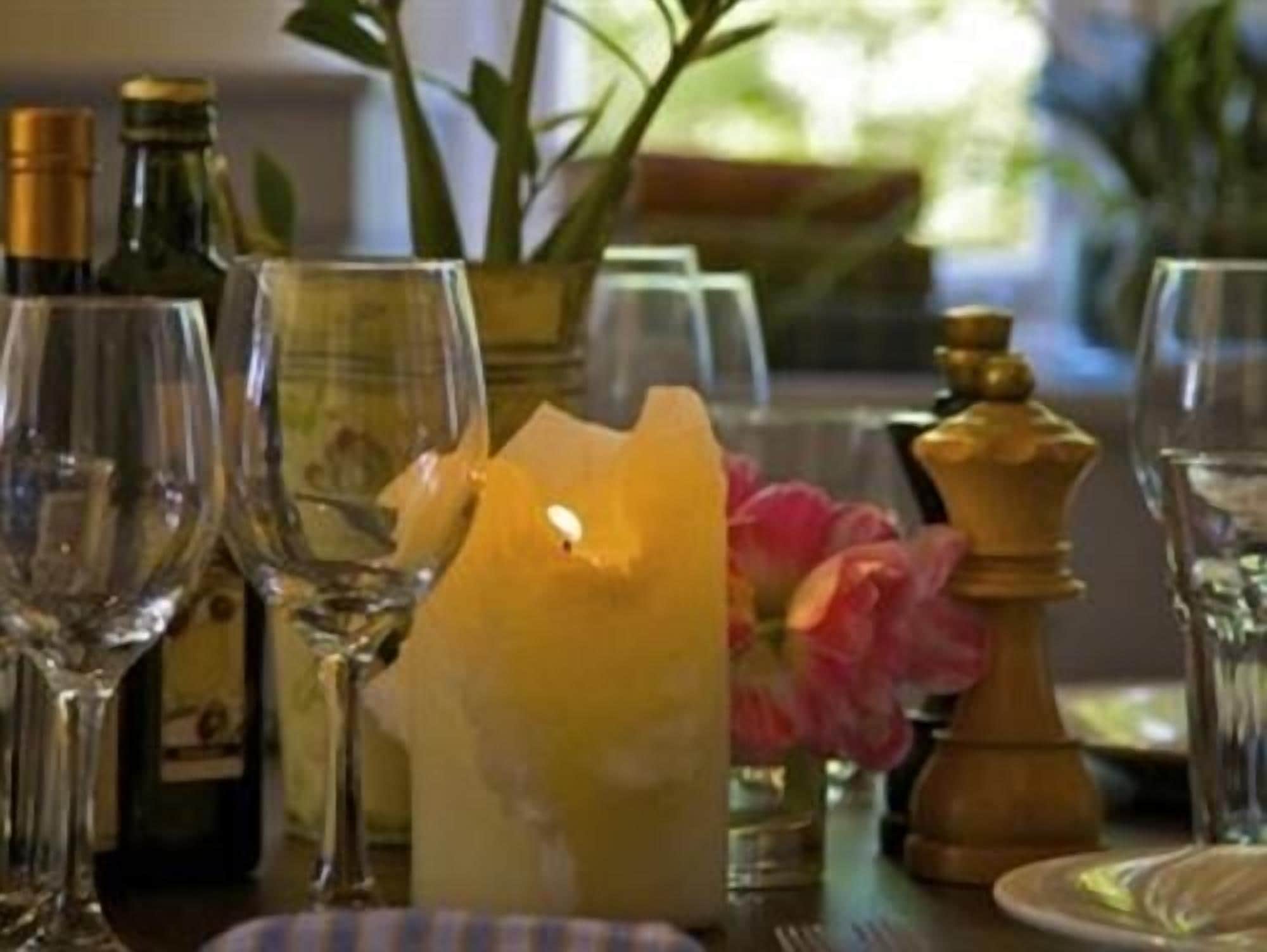 A dining table with wine glasses, a candle, and a salt and pepper shaker.