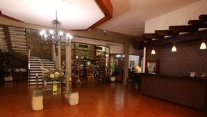 Eine geräumige Lobby mit Holzboden, einer Rezeption, einem Chandelier und einer Treppe zu den oberen Etagen.