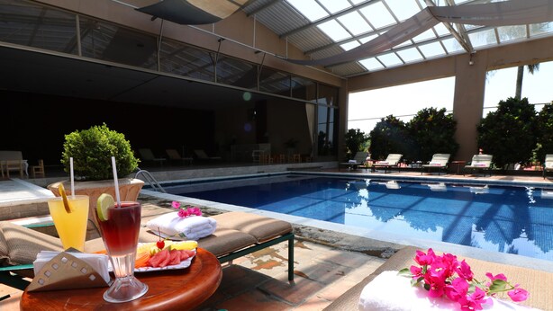 Ein Poolbereich mit Liegestuhl, Tisch mit Getränken und Snacks sowie einem Handtuch mit Blumen.