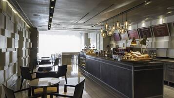 Ett modernt café med en central bardisk, sittplatser och en meny som visas på en anslagstavla.
