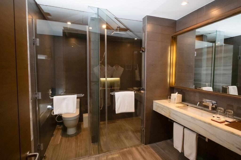 A modern bathroom with a glass-enclosed shower, a marble sink, and a large mirror.