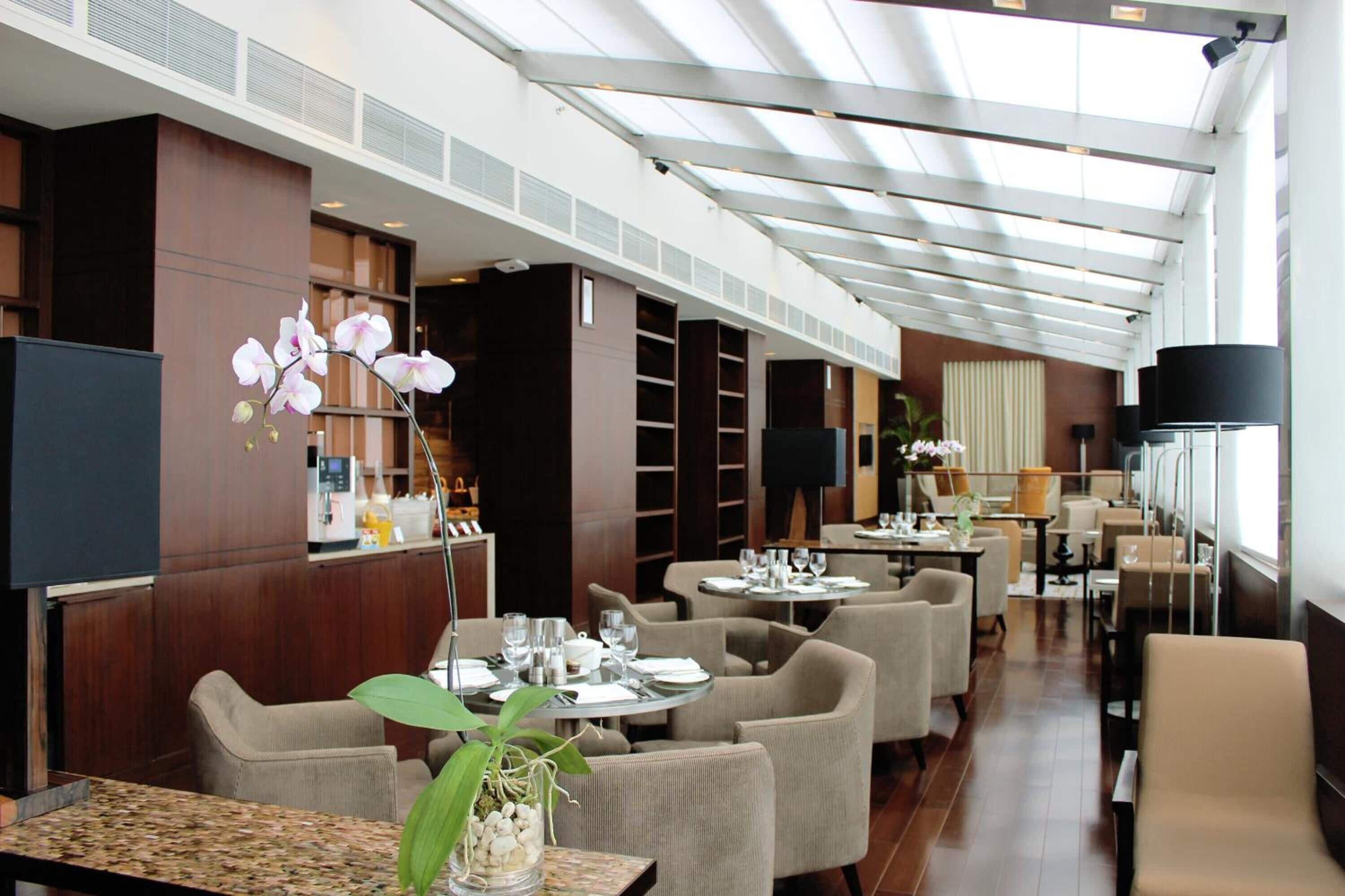 A spacious hotel lobby with multiple seating areas, a large chandelier, and a modern architectural design.