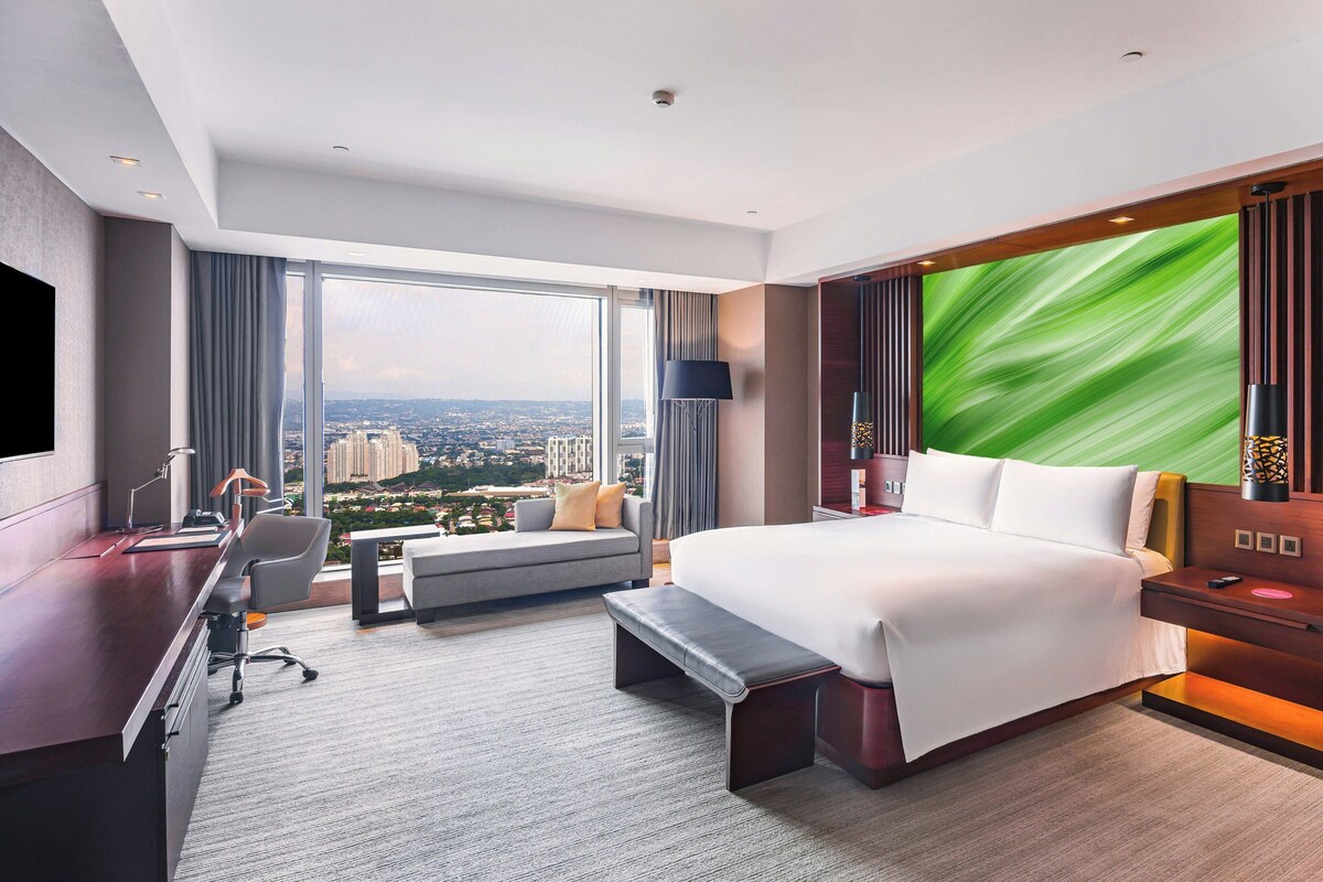 Una habitación de hotel moderna con una cama grande, un escritorio y vistas a la ciudad.
