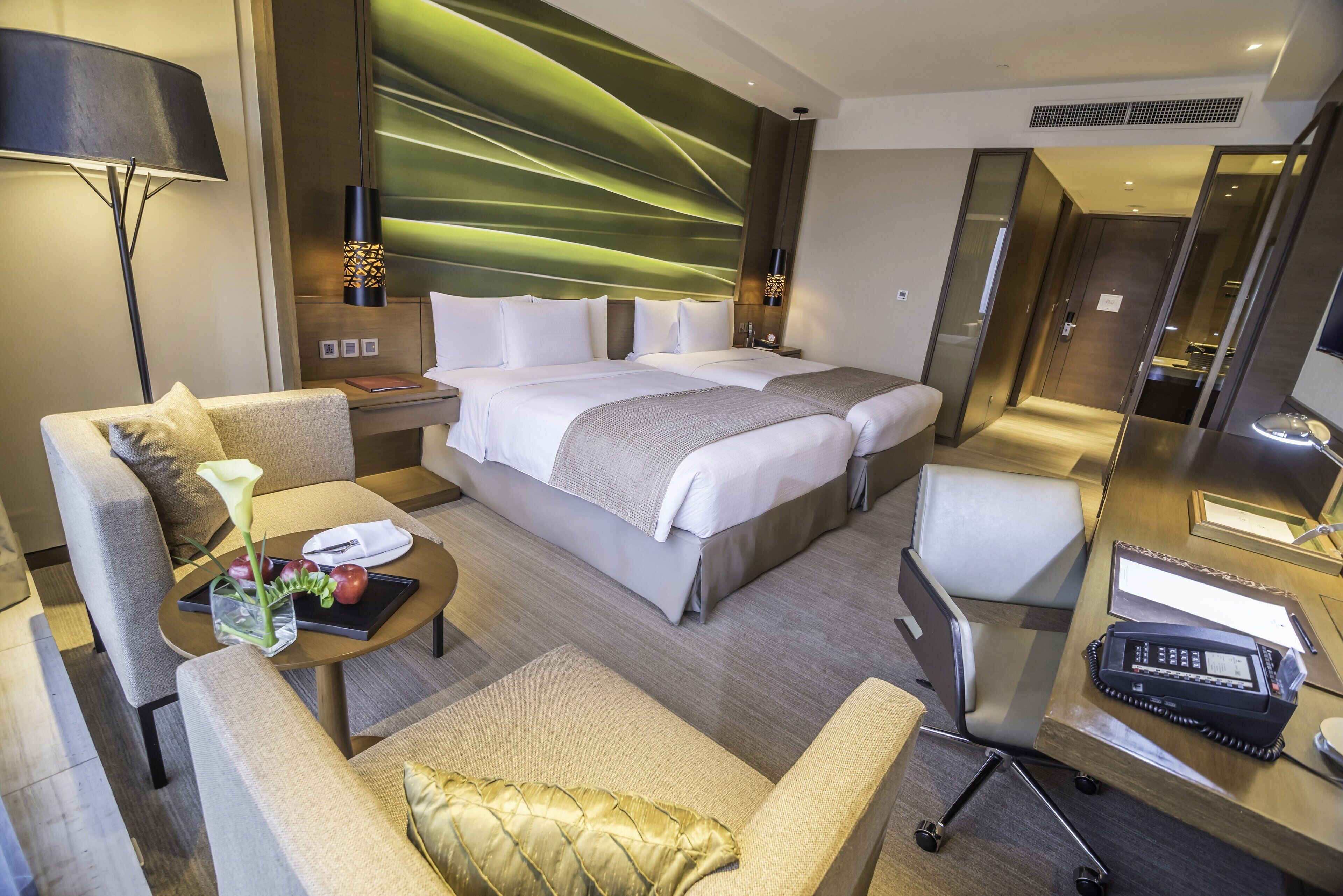 Une chambre d’hôtel moderne avec un grand lit, un canapé, un bureau avec un téléphone et un miroir.