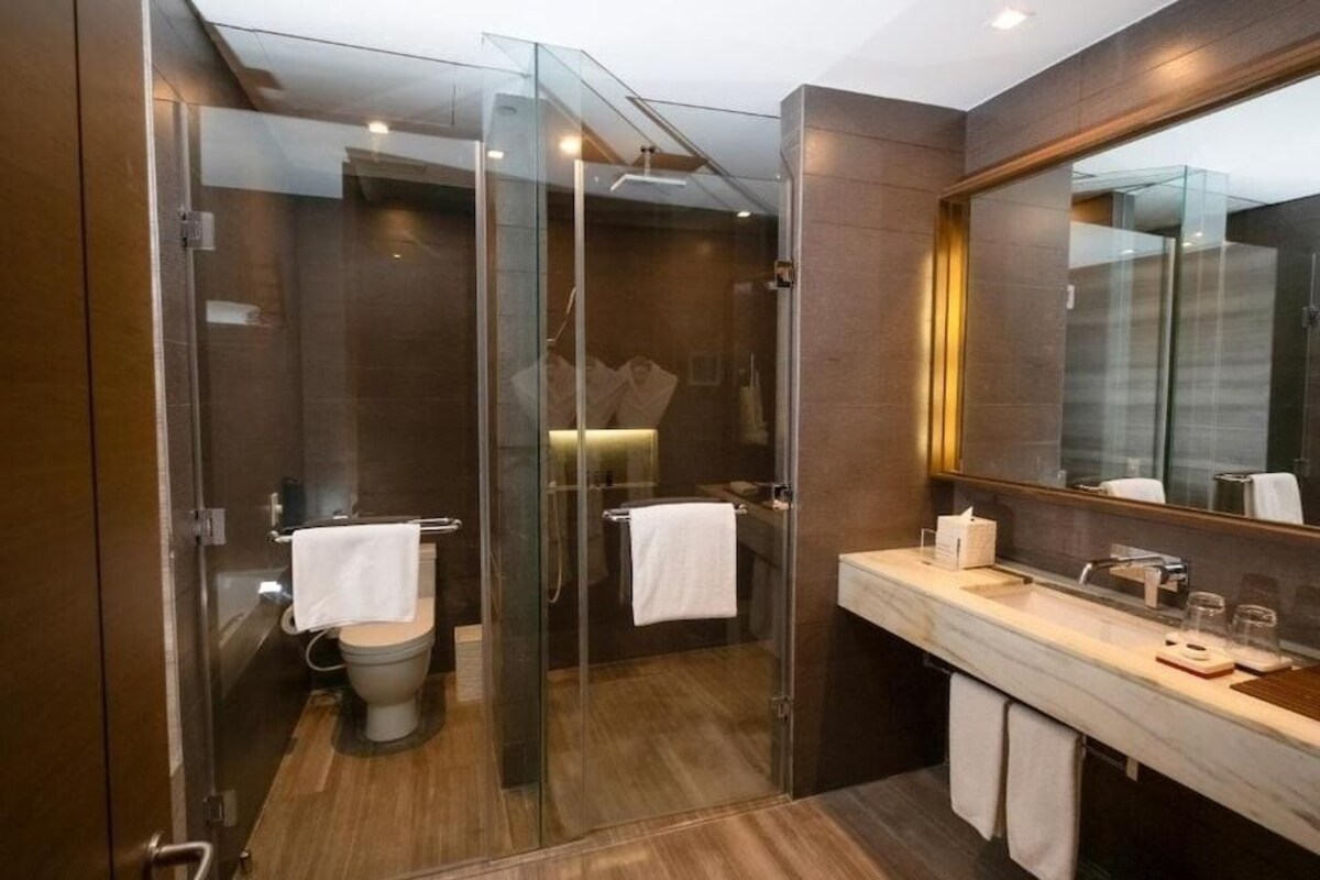Un baño moderno con ducha de vidrio, lavamanos de mármol y un espejo grande.
