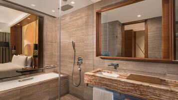 Un baño moderno con ducha envuelta en vidrio, tocador de mármol y un espejo grande.