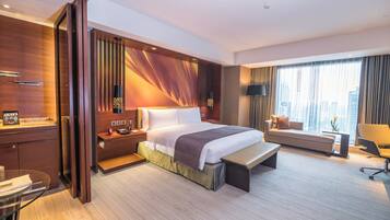 Una habitación de hotel moderna con una cama grande, un escritorio, un sofá y vistas a la ciudad.