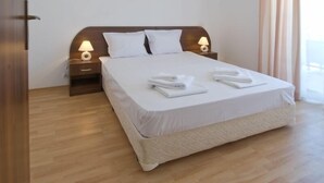 A neatly made bed with white linens and towels, two bedside lamps, and a wooden headboard. - Aparthotel Lighthouse (Sveti Vlas)