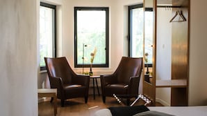 A hotel room with a bed, two chairs, a small table, and a wardrobe. - Gasthof Kapelhof (Erpe-Mere)