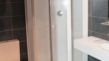 Une salle de bain comprenant des toilettes, un espace douche et un lavabo avec un miroir.
