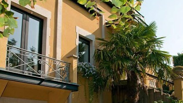 A two-story building with a balcony, a wooden table and chairs, and a well-maintained garden. - Gasthof Kapelhof (Erpe-Mere)