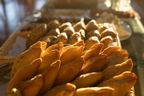 Una mesa con una variedad de productos de panadería, incluyendo pan y pasteles.