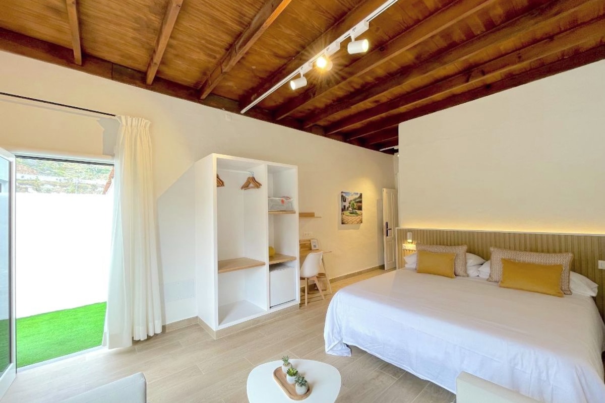 Habitación de hotel con cama, escritorio, armario y una pequeña mesa con bandeja.