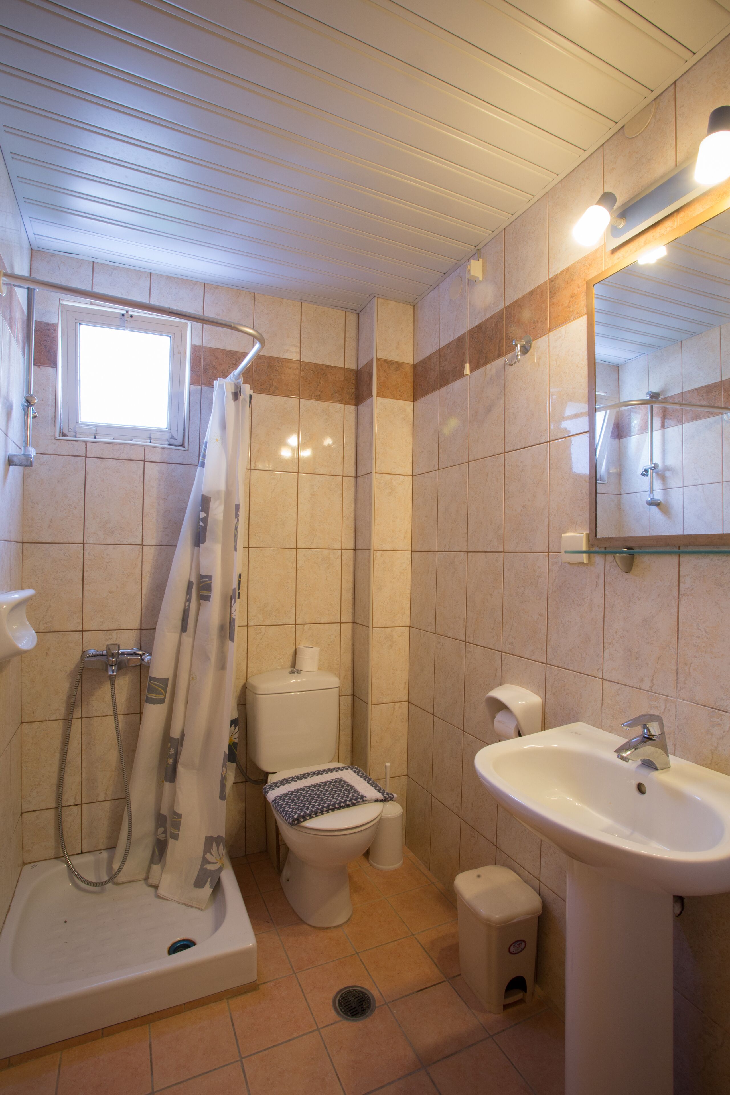 A bathroom with a bathtub, toilet, sink, and a window above the toilet.