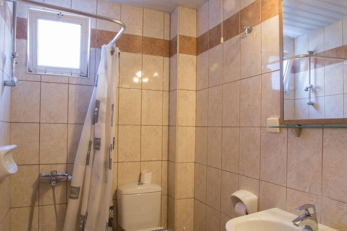 A bathroom with a shower, toilet, sink, and a window.