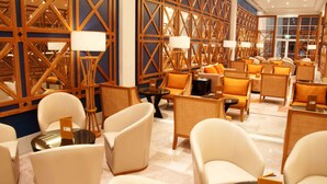 A hotel lobby with a modern design, featuring a mix of seating arrangements and a decorative wooden wall. - Salalah Gardens Hotel Managed by Safir Hotels & Resorts  (Salalah)