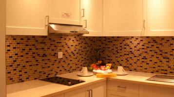 A kitchen with white cabinets, a tiled backsplash, and a central island with a sink and fruit bowl.
