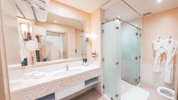 A modern bathroom with a large mirror, dual sinks, a glass shower enclosure, and a toilet.