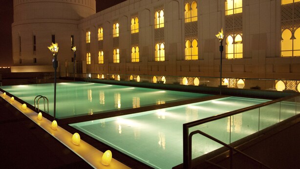 A swimming pool with a long, narrow shape, surrounded by a walkway with evenly spaced lights. - Salalah Gardens Hotel Managed by Safir Hotels & Resorts  (Salalah)