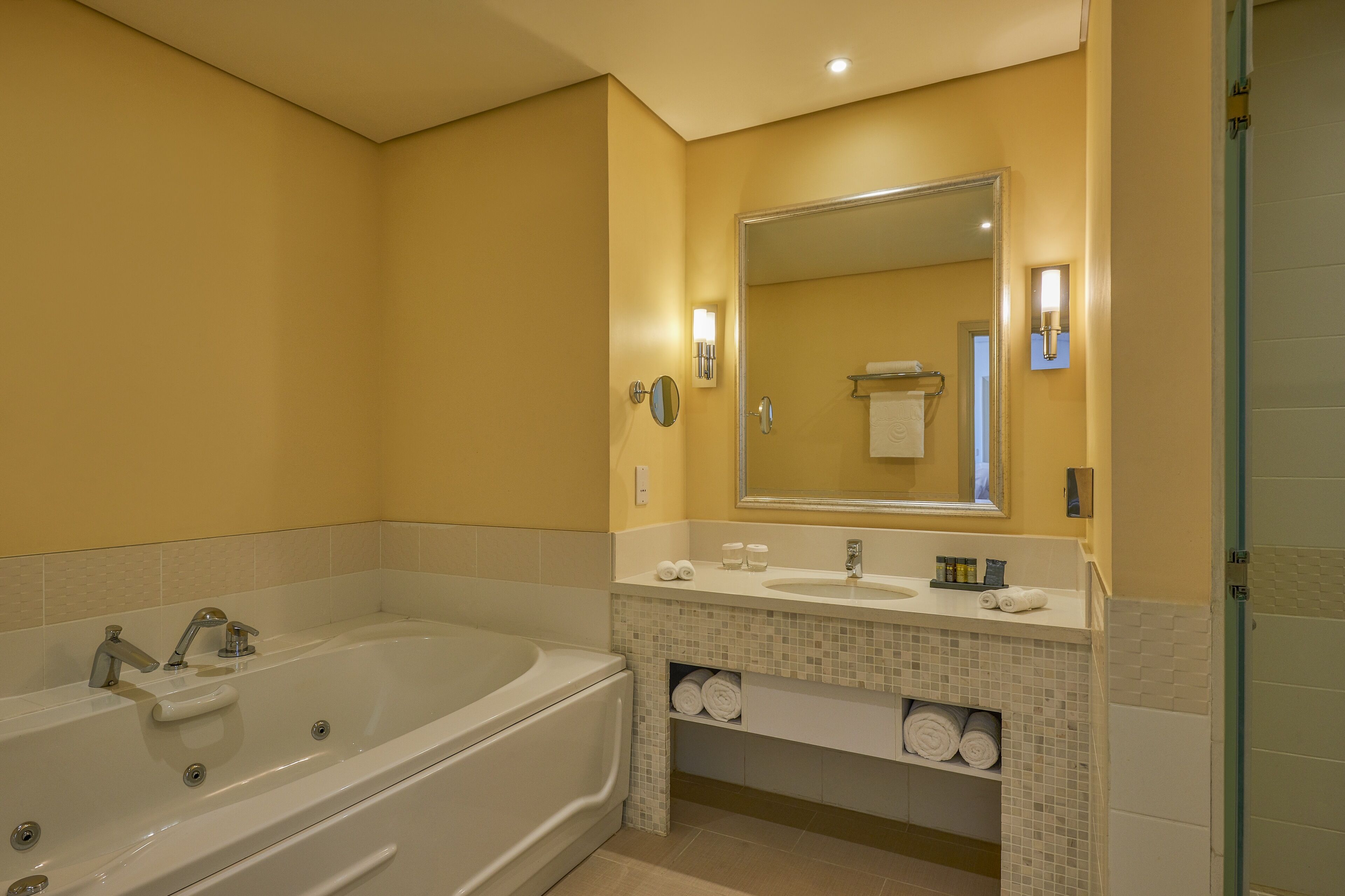 A modern bathroom with a large bathtub, two sinks, a mirror, and a towel rack.