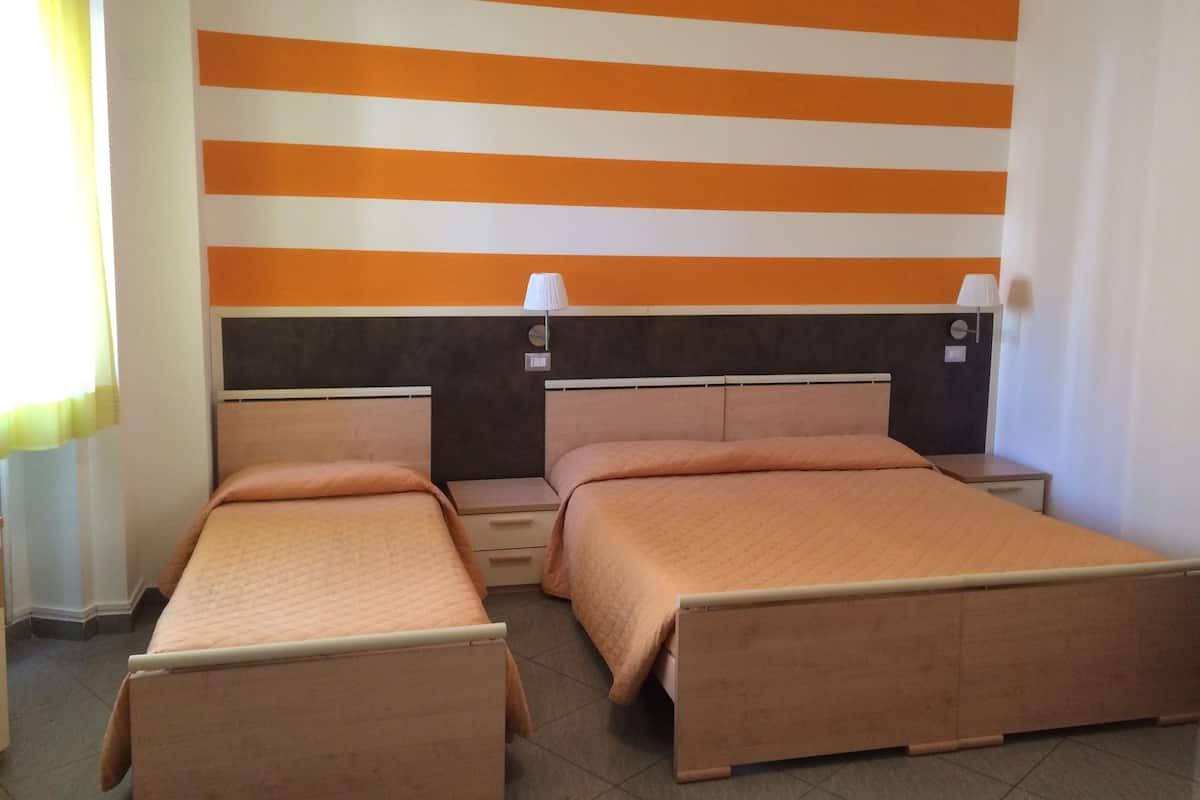 A hotel room with two beds, a striped wall, and a window with curtains.