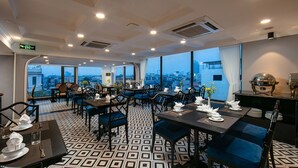 Un comedor con mesas dispuestas para cuatro, sillas tapizadas en azul y piso estampado.