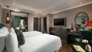 Habitación de hotel con dos camas, un escritorio, un televisor y un espejo.