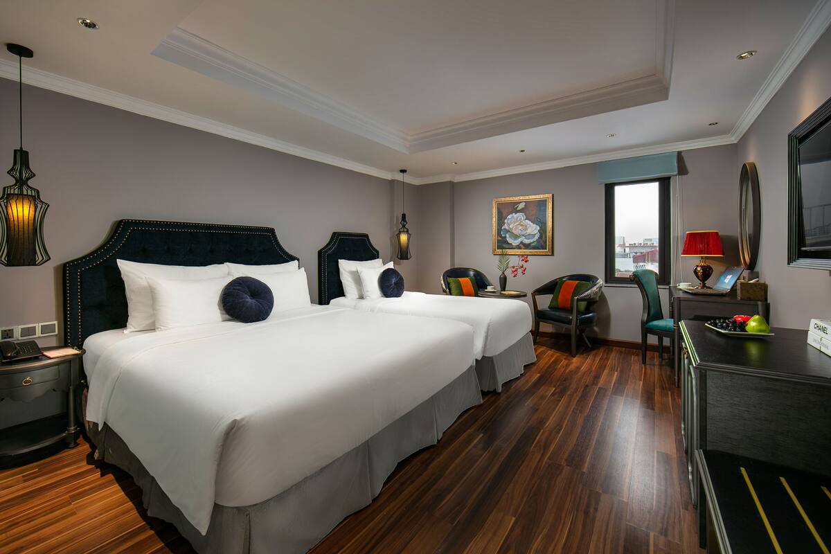 A hotel room with a large bed, a desk, a chair, and a view of the city.
