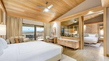 Habitación de hotel con una cama grande, un escritorio, una silla, un espejo y vista a la playa.
