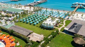 An aerial view of a resort with multiple pools, beach areas, and a marina. - Regnum Carya - All Inclusive (Serik)