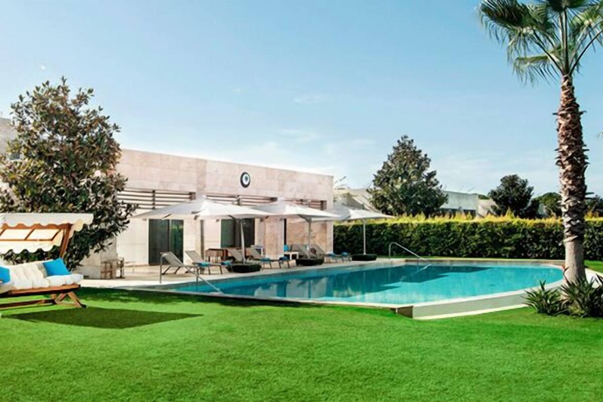 A swimming pool, a covered seating area, and a building with a modern design.