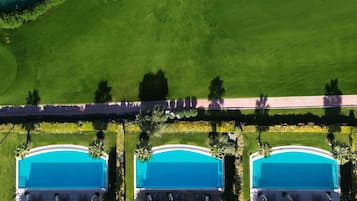 Three pools surrounded by lush lawns and palm trees, connected by a pathway.