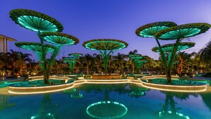 A pool area with illuminated umbrellas and a circular seating arrangement. - Regnum Carya - All Inclusive (Serik)