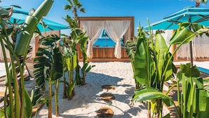 A beachside lounge area with a wooden deck, white curtains, and a view of the ocean. - Regnum Carya - All Inclusive (Serik)