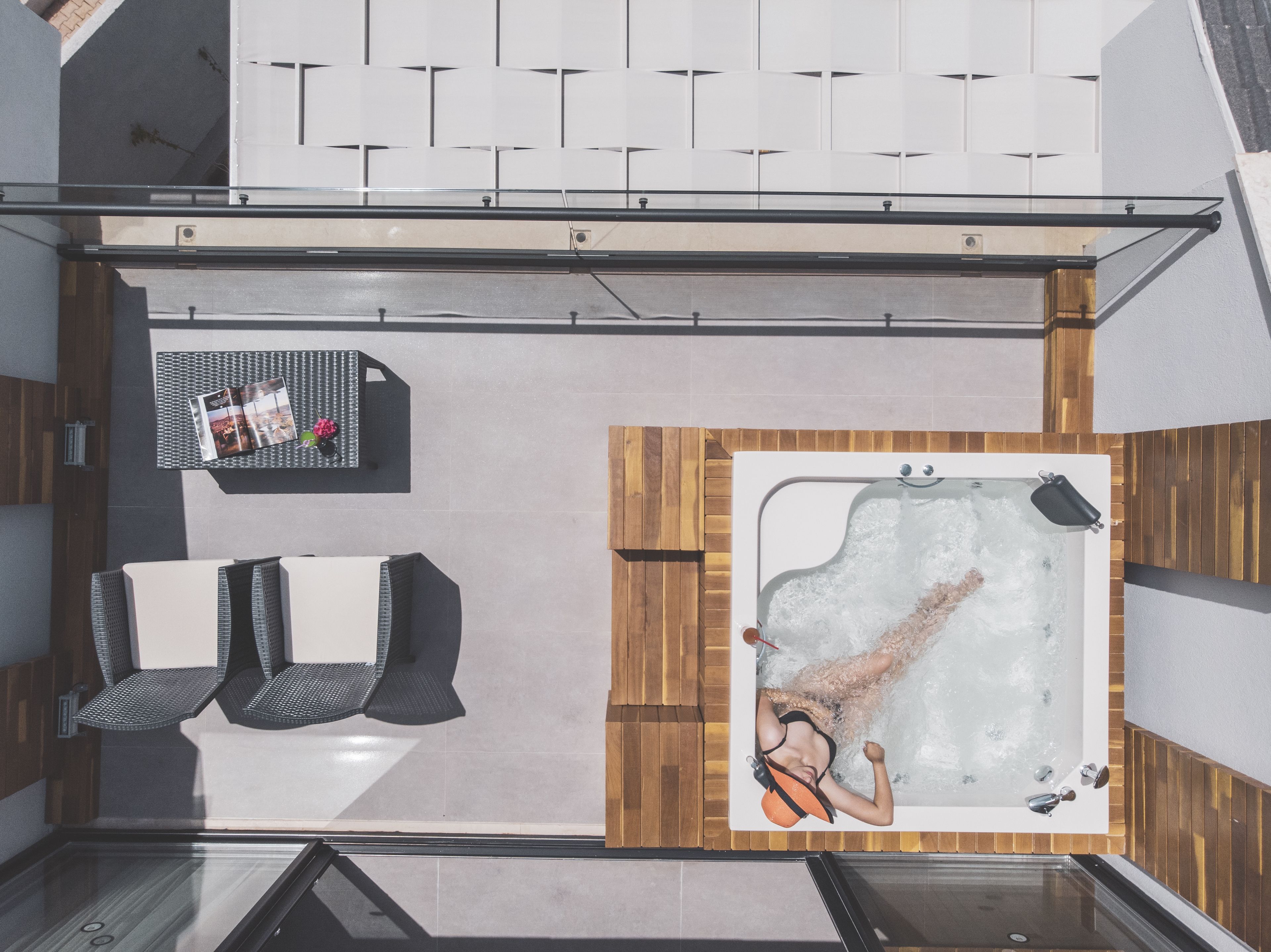 Un área de spa moderna con un jacuzzi, dos sillones de descanso y un mueble para revistas.