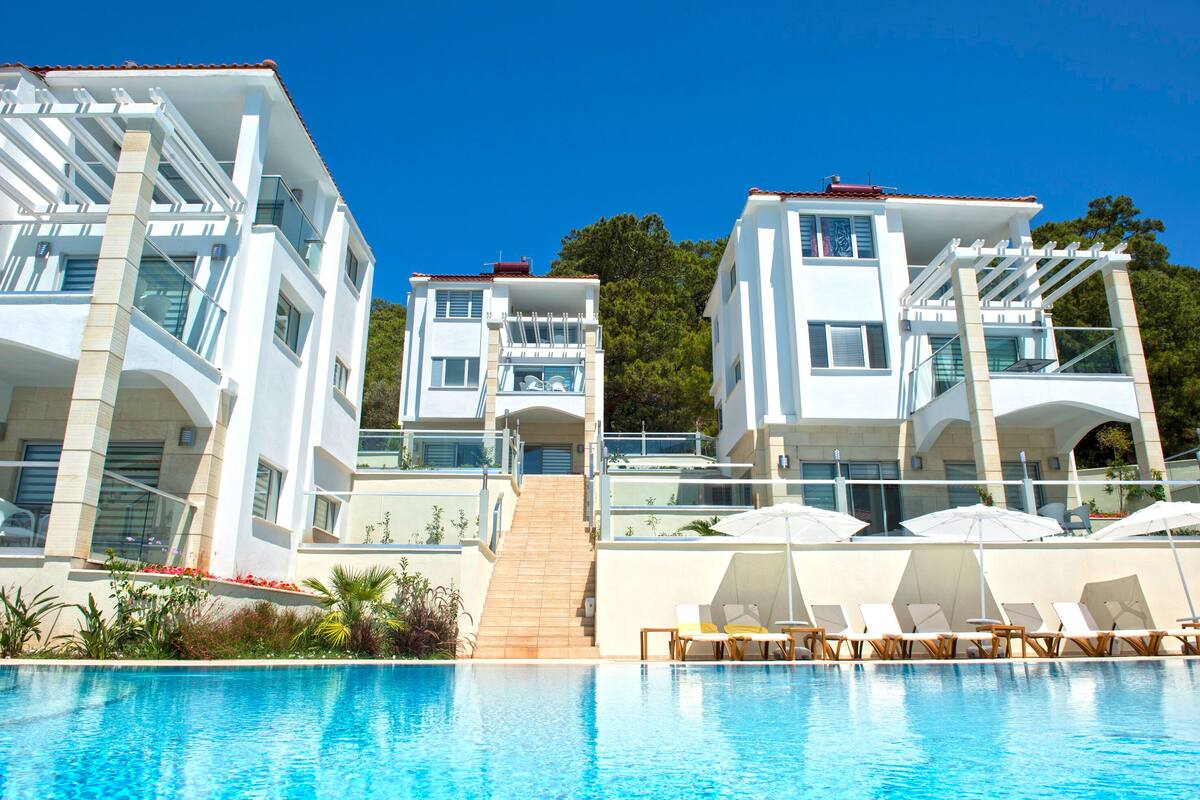 A modern hotel with a swimming pool, multiple balconies, and outdoor seating areas.