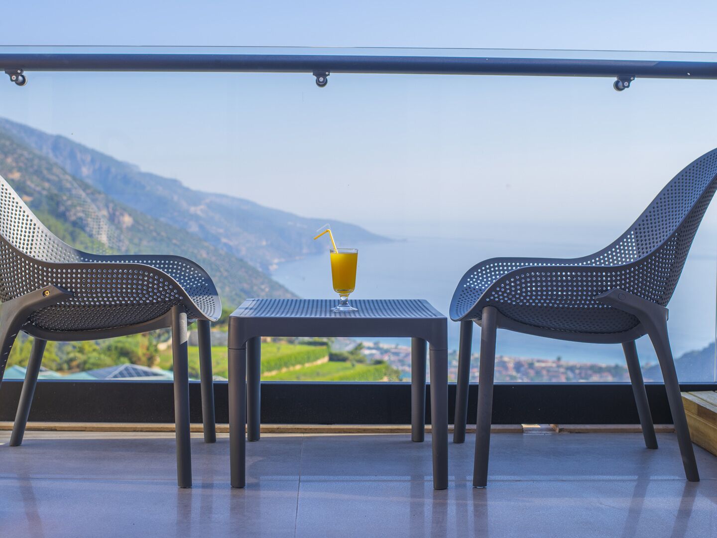 A balcony with two chairs and a table, overlooking a scenic landscape.