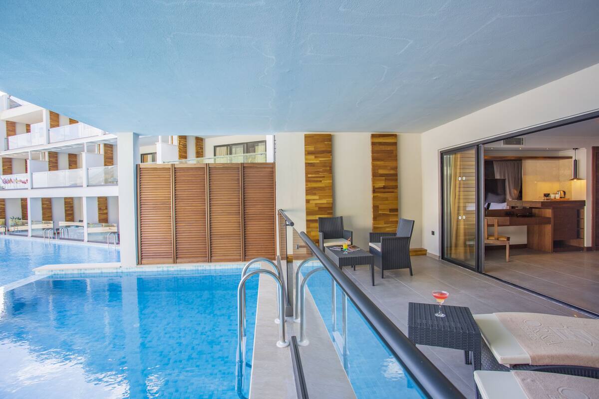 A hotel pool area with a clear view of the pool, lounge chairs, and a dining area.