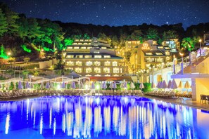 A hotel with a swimming pool, outdoor seating, and a night sky. - Orka Sunlife Resort hotel and Aquapark (Fethiye)